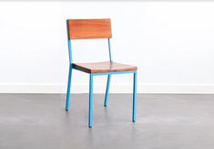 a wooden chair sitting on top of a cement floor next to a white wall in an empty room