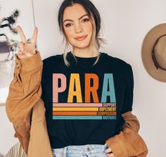 a woman wearing a black shirt with the word para written on it in front of her