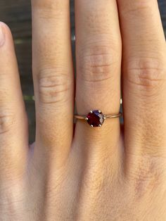 a woman's hand with a ring on it and a red stone in the middle