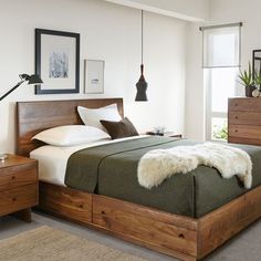 a bedroom with a bed, nightstands and pictures on the wall above it is shown