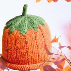 an orange knitted pumpkin hat with leaves around it