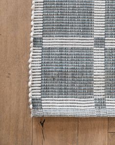 a close up of a rug on a wooden floor with white and gray squares in the middle