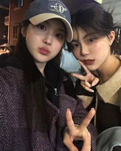 two young women posing for the camera with their fingers in the shape of peace signs