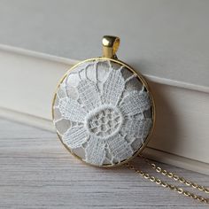 a white lace doily is hanging from a gold chain