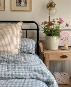 a bed with blue and white checkered bedspread next to a small wooden table