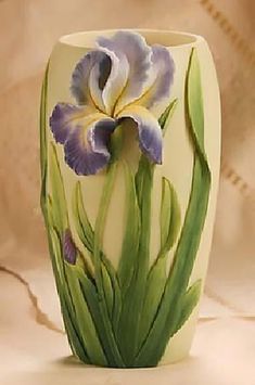 a white vase with purple and yellow flowers painted on the side, sitting on a marble surface