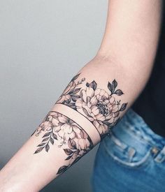 a woman's arm with flowers on it and a band around the wrist tattoo