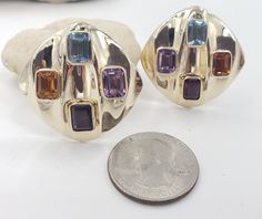 Title: Multicolor Gemstones Round Corner Square 14KT Yellow Gold Omega Clip Earrings Designer: Unbranded Material14KT Stamped Style: Vintage Gemstone Details All measurements are approximate and may vary slightly from the listed dimensions.1ar Approximately 5mm x 4mm each 1Amethyst Rectangular 1 Blue Topaz Rectangular 1 Orange Citrine Rectangular 1 Garnet Rectangular Estimated Measurements of the item30.23mm x 20.23mm x 5.83mm Estimated Total Weight of the Item DWT: 7.6 Grams: 11.7 Condition: Pr Oval Multicolor Earrings For Anniversary, Multicolor Oval Earrings For Anniversary, Multicolor Gemstone Accented Earrings For Formal Occasions, Multicolor Gemstone Earrings For Anniversary, Oval Multicolor Anniversary Earrings, Gold Earrings With Stones For Formal Occasions, Luxury Gold Earrings With Stones, Multicolor Multi-stone Earrings For Anniversary, Formal Multicolor Gemstone Earrings