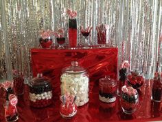 the candy bar is decorated with red and white candies, lollipops, and other sweets