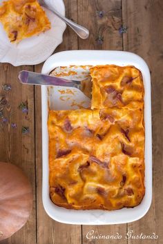 a casserole dish with ham and cheese in it on a wooden table next to a pumpkin