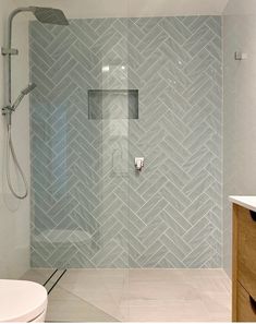 a bathroom with a shower, toilet and sink in the corner on the wall is a herringbone pattern