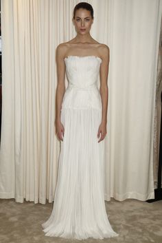 a woman standing in front of a white curtain wearing a dress with pleated skirt