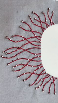 a piece of cloth with beads on it and a white plate in the middle that has red string attached to it