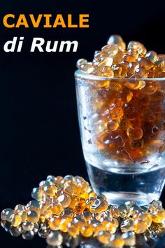 a glass filled with lots of yellow bubbles on top of a table next to a black background