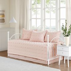 a white daybed with pink bedding and pillows