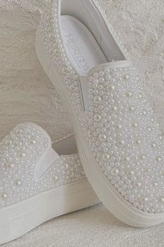 a pair of white shoes with pearls on them