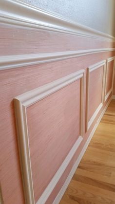 a wooden paneled wall with white trim on the top and bottom panels, along with wood flooring