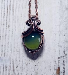 I handcrafted both the glass stone, and the wire wrap, right here in the USA.  The stone was made using premium glass color and an oxygen/propane torch.  I wrapped the stone in curvy copper wire for this one of a kind pendant that you will not find anywhere else.   The opalescence of this pendant is an enchanting phenomenon where light reveals a mesmerizing play of colors and hues. This delicate dance of iridescence creates a stunning visual effect, with shifting tones that range from deep emerald green to vibrant slyme yellow. The beauty of opalescence lies in its ability to capture and reflect light in a way that seems almost magical, adding depth and intrigue to everything it touches.  Designed for the connoisseur of fine jewelry, this exquisite piece features vibrant, opalescent hues t Artisan Green Recycled Glass Jewelry, Fusion Wire Wrapped Necklace For Gift, Fusion Style Wire Wrapped Necklace For Gift, Green Glass Wire Wrapped Necklaces, Green Glass Wire Wrapped Necklace, Green Wire Wrapped Czech Glass Necklace, Green Wire Wrapped Glass Jewelry, Wire Wrapped Green Glass Jewelry, Bohemian Wire Wrapped Glass Jewelry