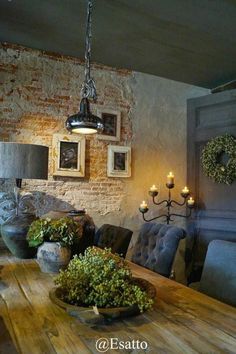 a dining room table and chairs with candles on the wall in front of an old brick wall