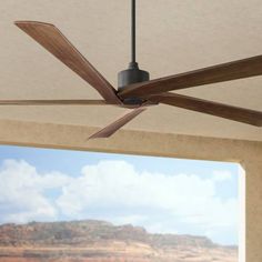 a ceiling fan is hanging from the ceiling in front of a window with mountains and blue sky