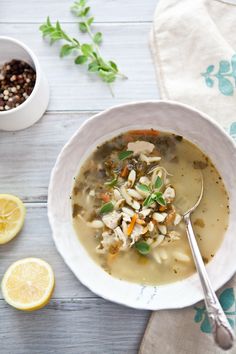 a white bowl filled with soup next to two lemons and some other food items