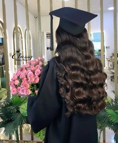 a woman with long hair wearing a graduation cap and gown in front of a mirror