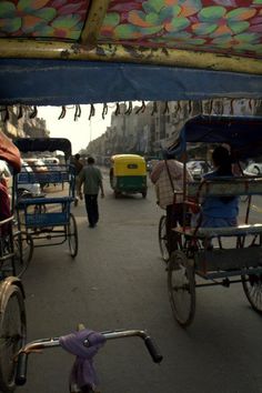 people are riding rickshaws down the street