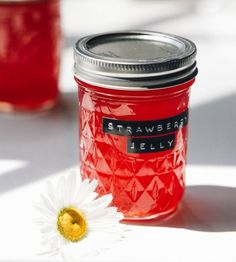 a glass jar filled with jelly next to a flower