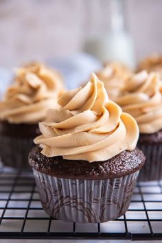 three cupcakes with frosting on a cooling rack