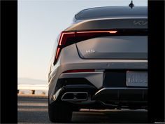 the rear end of a silver car with its tail lights on