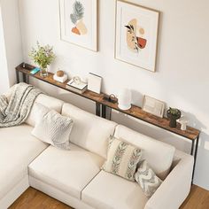 a living room with white couches and pictures on the wall above them, along with wooden flooring