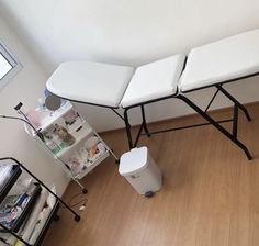 three white folding chairs sitting on top of a hard wood floor next to a trash can