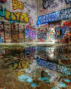 an abandoned building with graffiti all over the walls and floor, reflecting in puddles of water