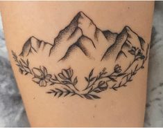 a tattoo with mountains and flowers on it