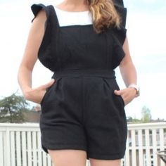 a woman in black and white jumpsuits with her hands on her hips, posing for the camera