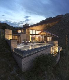 a house with a pool in the middle of it at night, surrounded by cacti and cactus