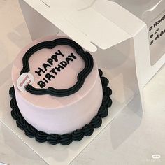 a birthday cake in the shape of a heart on top of a white box with black trim