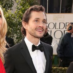 a man in a tuxedo standing next to a woman wearing a red dress