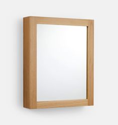 a mirror mounted on the wall with a wooden frame and light colored wood grained finish