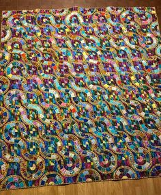 a multicolored quilt is laying on the floor in front of a wooden floor