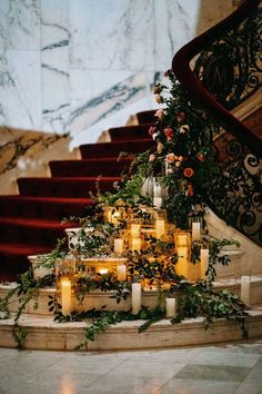 candles are lit in front of a staircase decorated with flowers and greenery on the steps