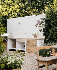 an outdoor kitchen with wooden furniture and greenery