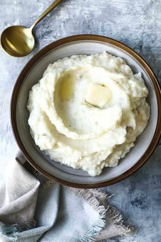 mashed potatoes in a bowl with butter on top and a spoon next to it