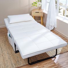 a white bed sitting on top of a hard wood floor next to a wooden table