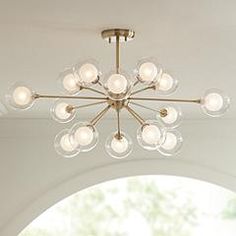 a chandelier hanging from the ceiling in a room with white walls and windows