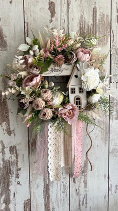 a wreath with flowers and a birdhouse hanging from it