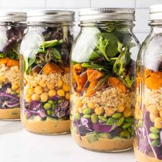 two mason jars filled with food sitting on top of a wooden table