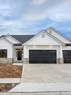 a white house with black garage doors and windows