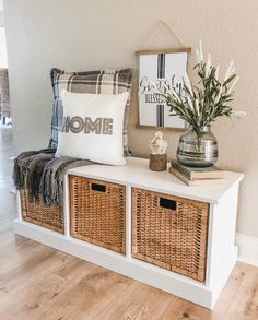 a white bench with wicker baskets on it and some flowers in a vase next to it