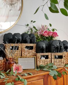 there are many black hats on display in the basket next to some flowers and a mirror